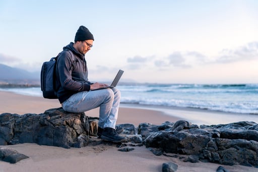 digital-nomad-working-on-his-laptop-outdoors-from-the-beach-at-sunset