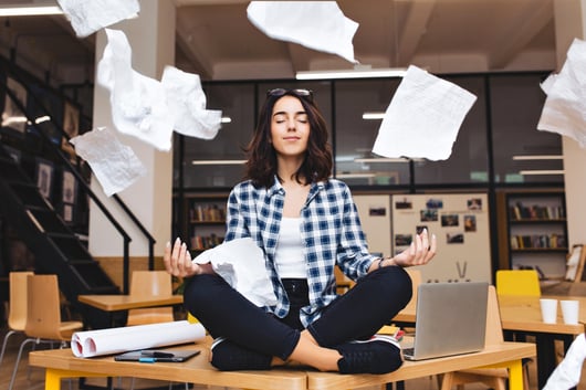 young-pretty-joyful-brunette-woman-meditating-on-table-surround-work-stuff-and-flying-papers-cheerful-mood-taking-break-working-studying-relaxation-true-emotions